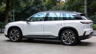 White NIO ES8 five-seat flagship SUV in side profile with panoramic glass roof, parked outside NIO House